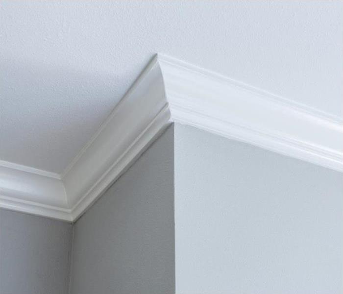 A close-up photo of crown molding against a grey wall